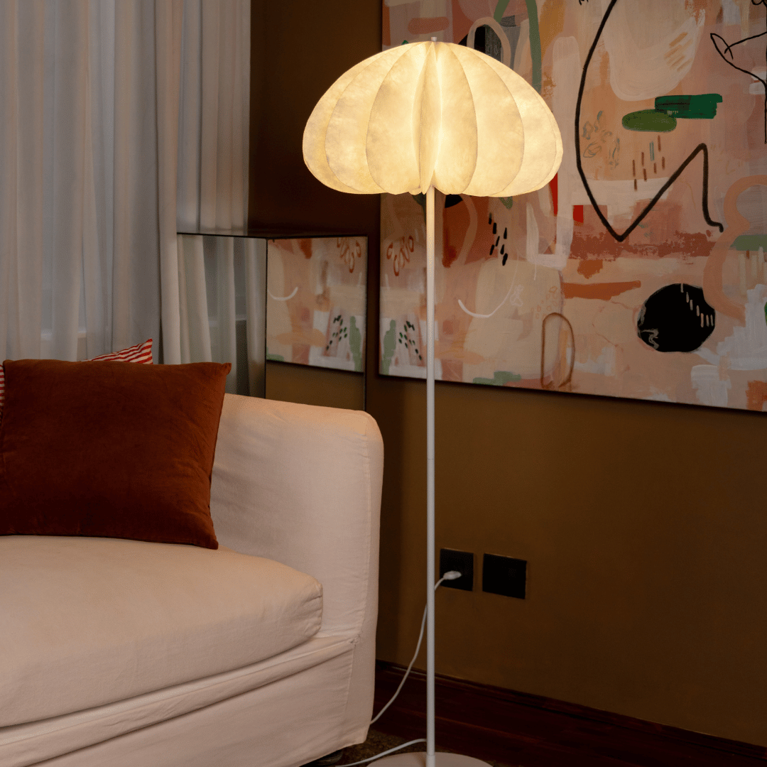 Daisy Floor lamp with a warm light in a room with a beige sofa and abstract wall art.
