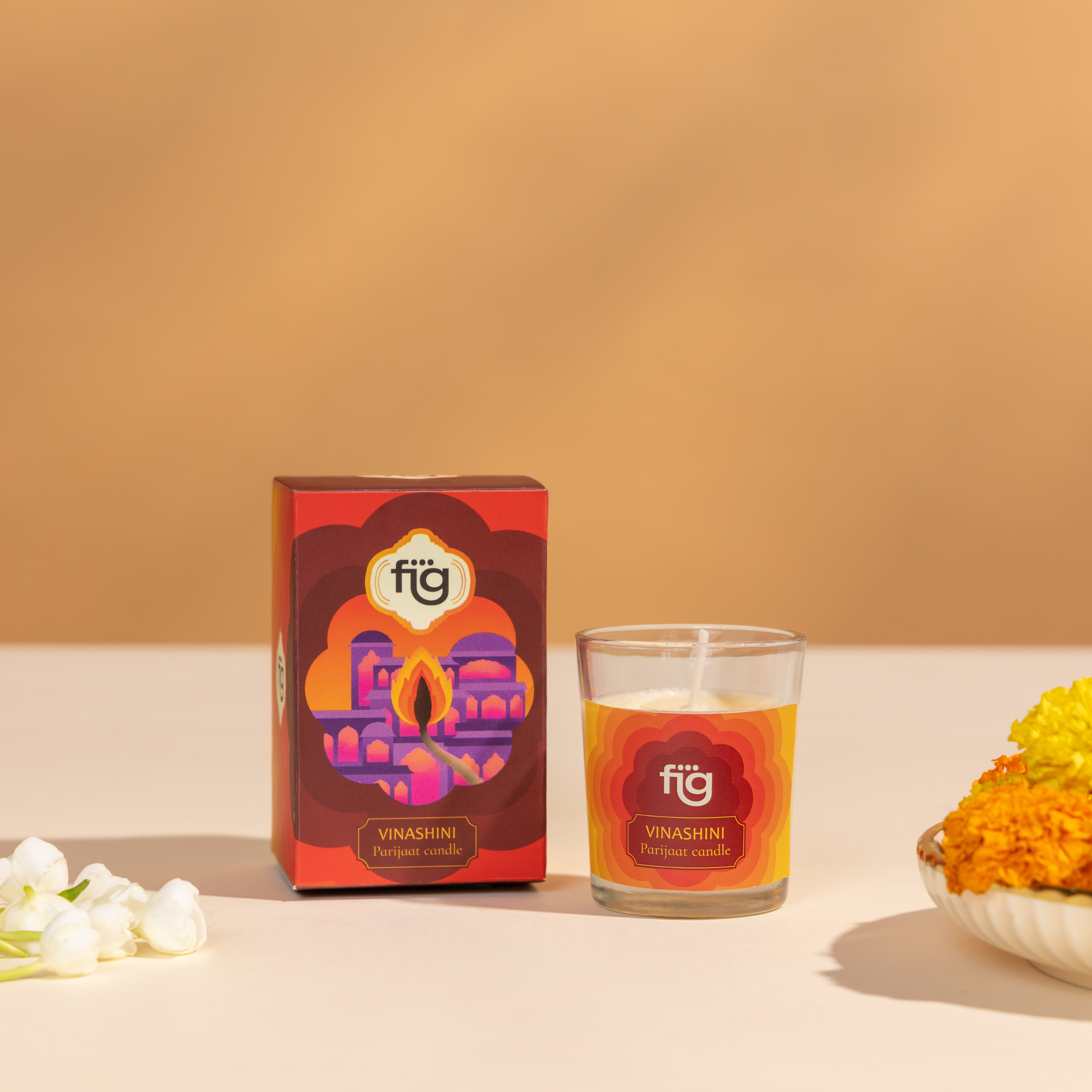 Scented candle for Diwali with packaging and flowers on a beige background