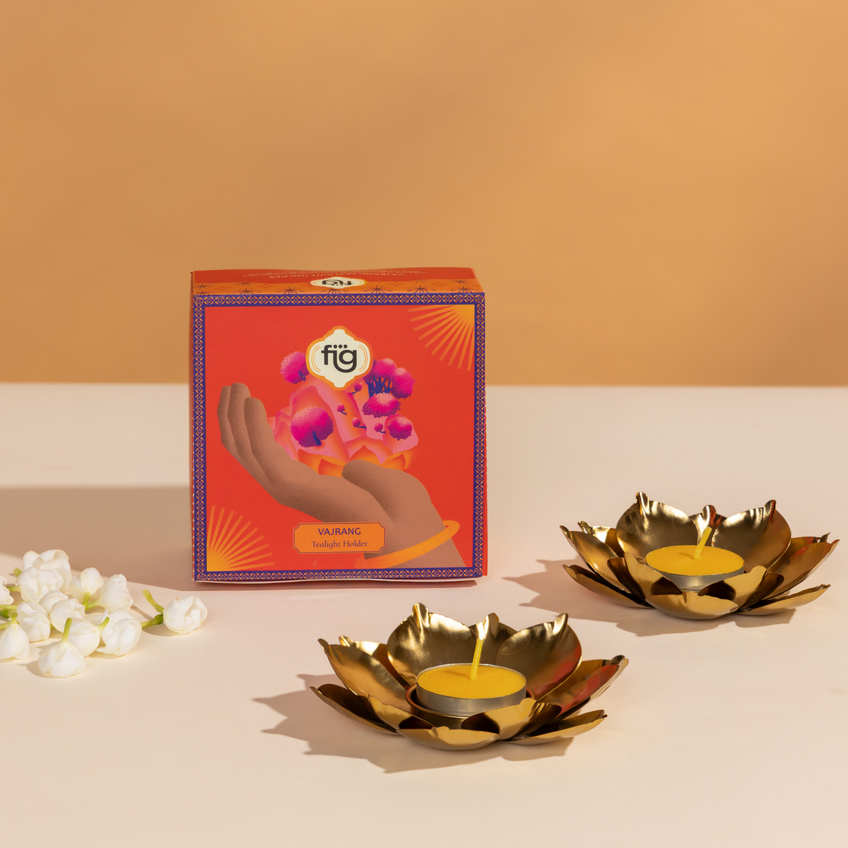 Gold lotus-shaped candle holders for Diwali with a decorative box on a beige background