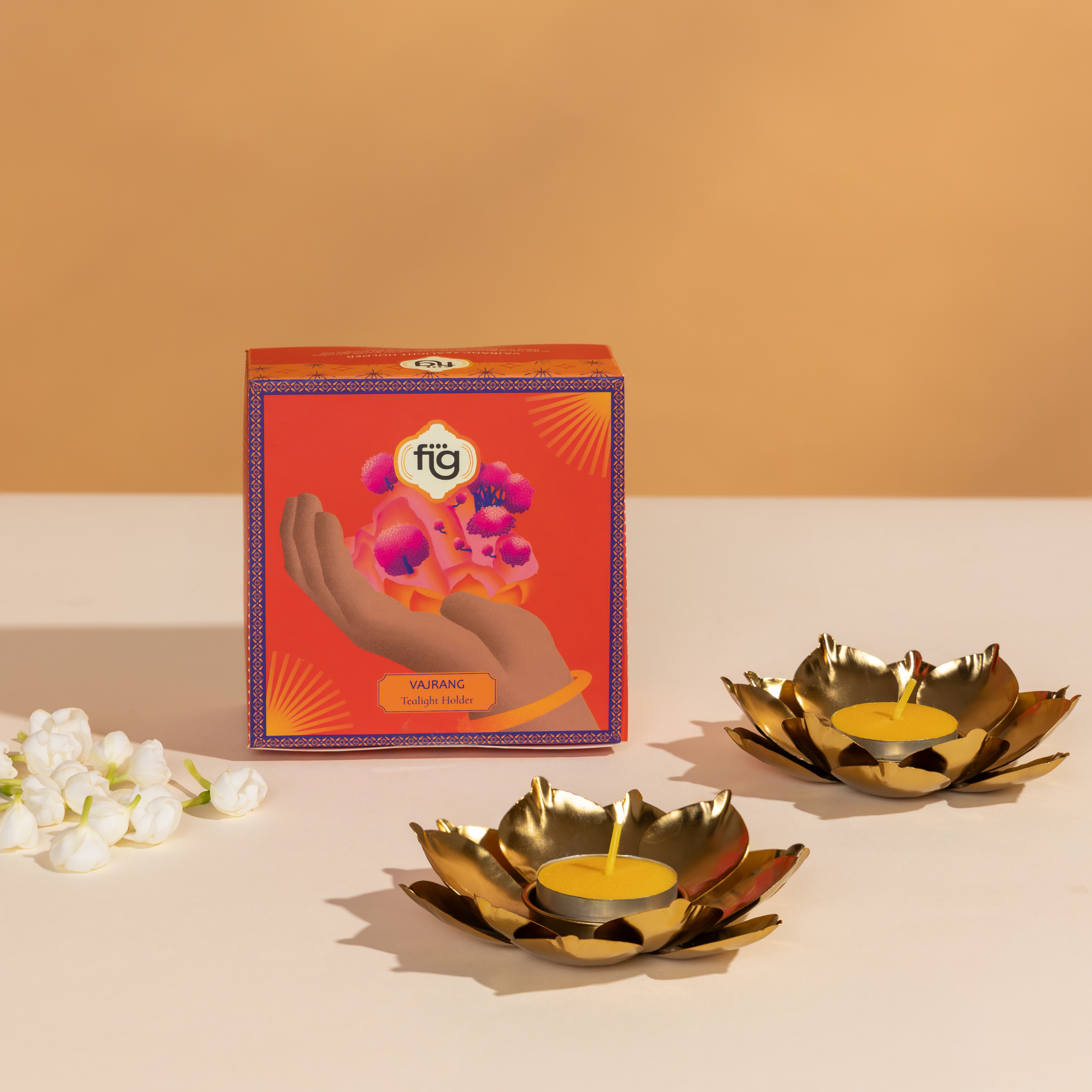 Gold lotus-shaped candle holders for Diwali with a decorative box on a beige background