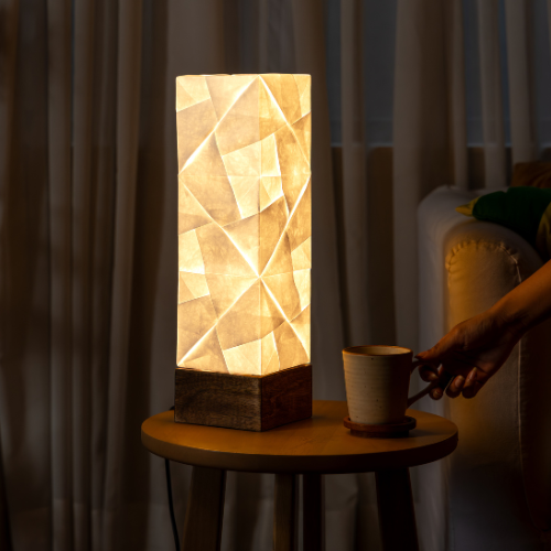 Solobe Tetris Desk Lamp with geometric pattern on a small round table next to a cup, in a dimly lit room.