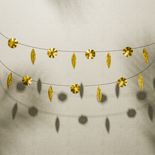 Gold leaf garland on a textured beige wall, Golden decorative toran for Diwali