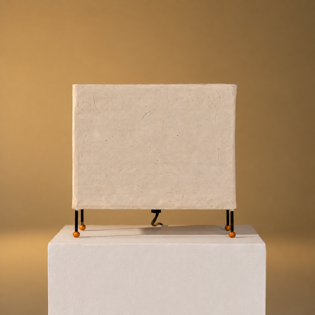 A rectangular canvas print with a textured off-white surface, supported by thin black metal legs with orange tips, displayed on a white pedestal against a warm beige background.